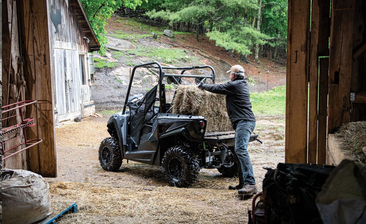 Farmer stacking hay bales on a UTV