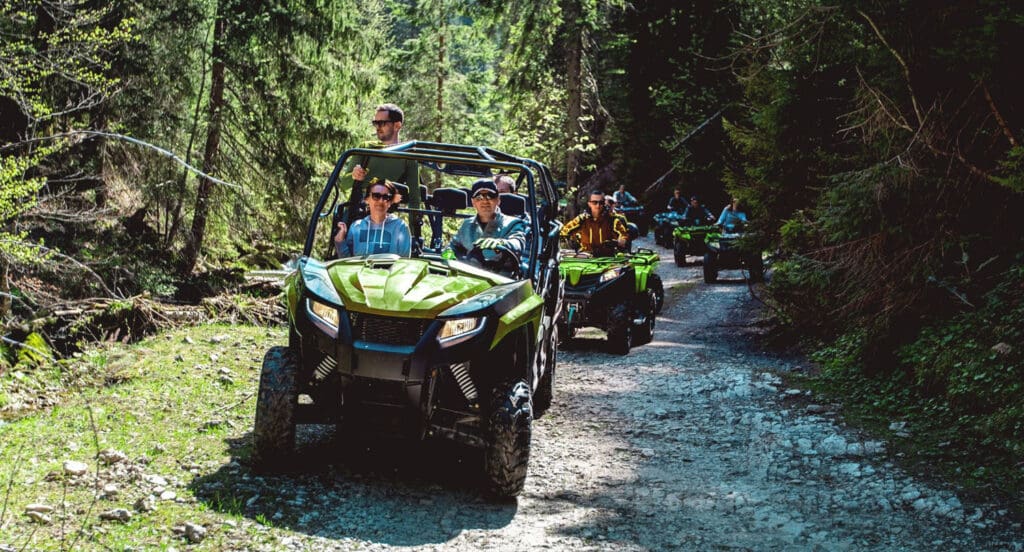 A group of riders navigating power sports vehicles, including ATVs and UTVs, through scenic forest trails in Ontario.